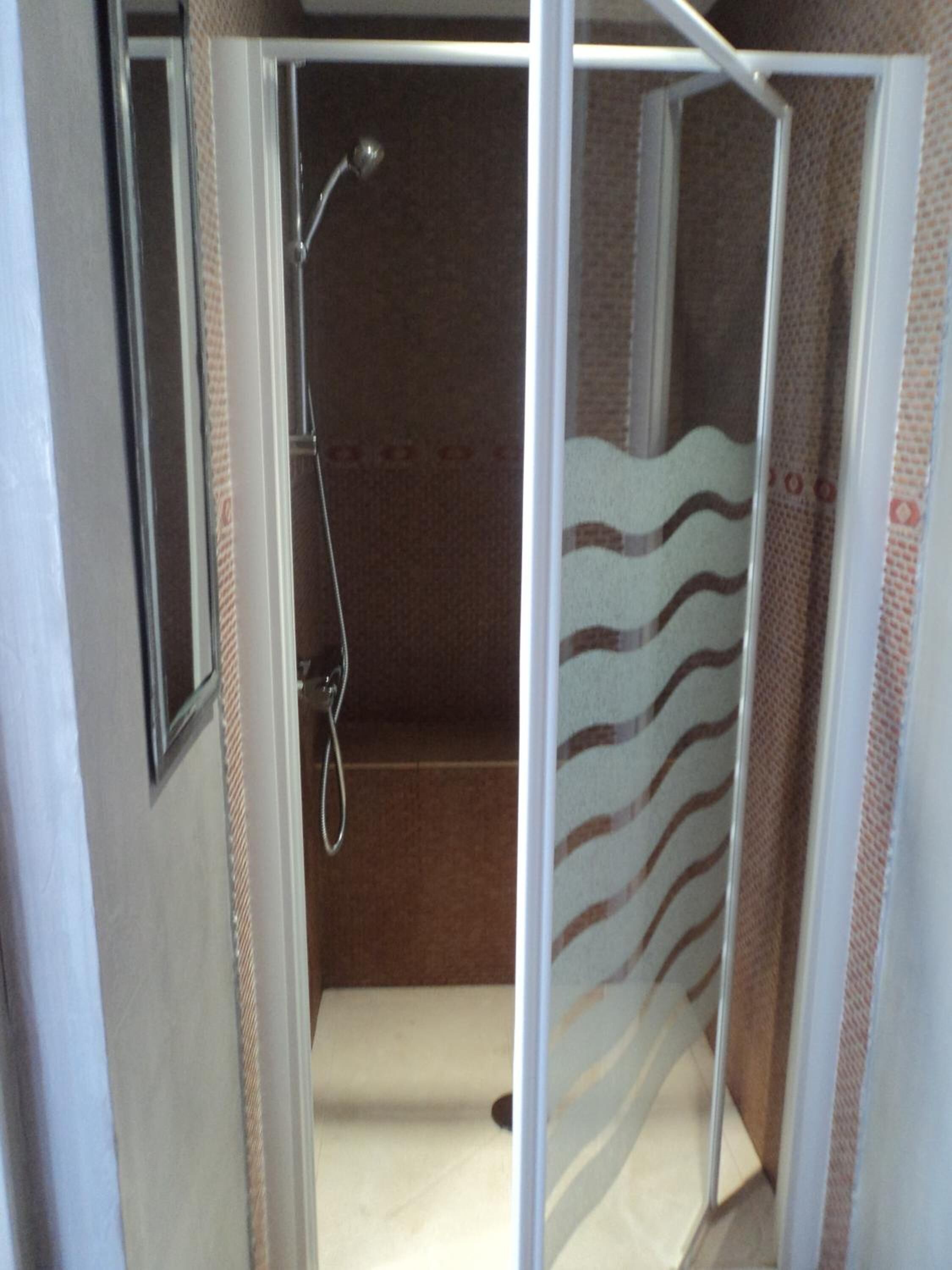 A shower enclosure with a showerhead and a towel rack.