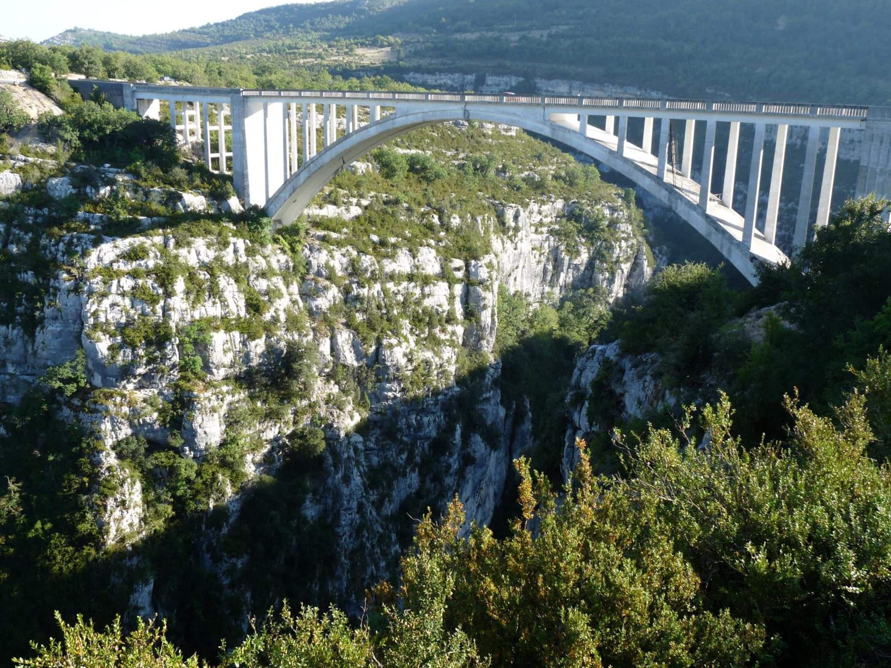 Un grand pont enjambant un profond canyon aux parois rocheuses et à la végétation clairsemée.