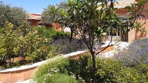 A garden with various plants and a building with a tiled roof. - Les Jardins de l'Ermitage (Les Salles-sur-Verdon)
