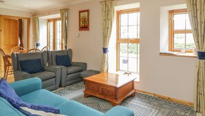 A living room with a sofa set, a wooden coffee table, and a patterned rug. - Kamba Cottage (Forfar)