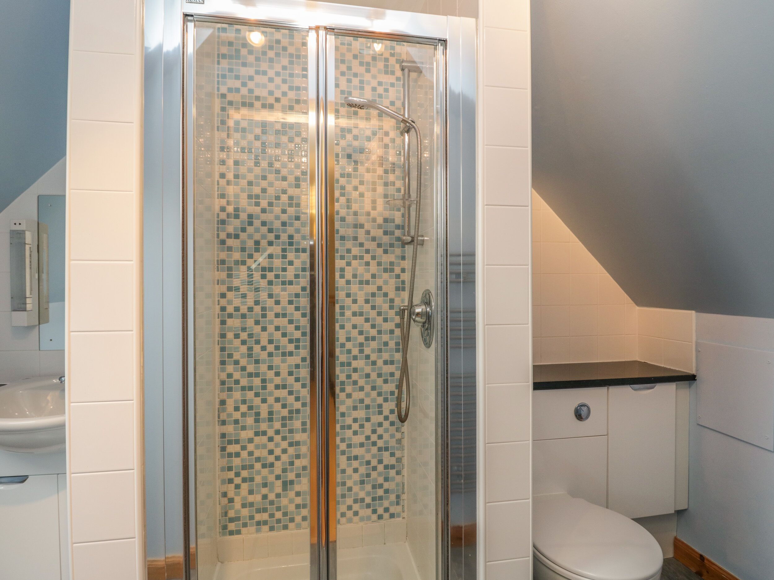 Un baño con ducha de vidrio, inodoro y lavamanos.