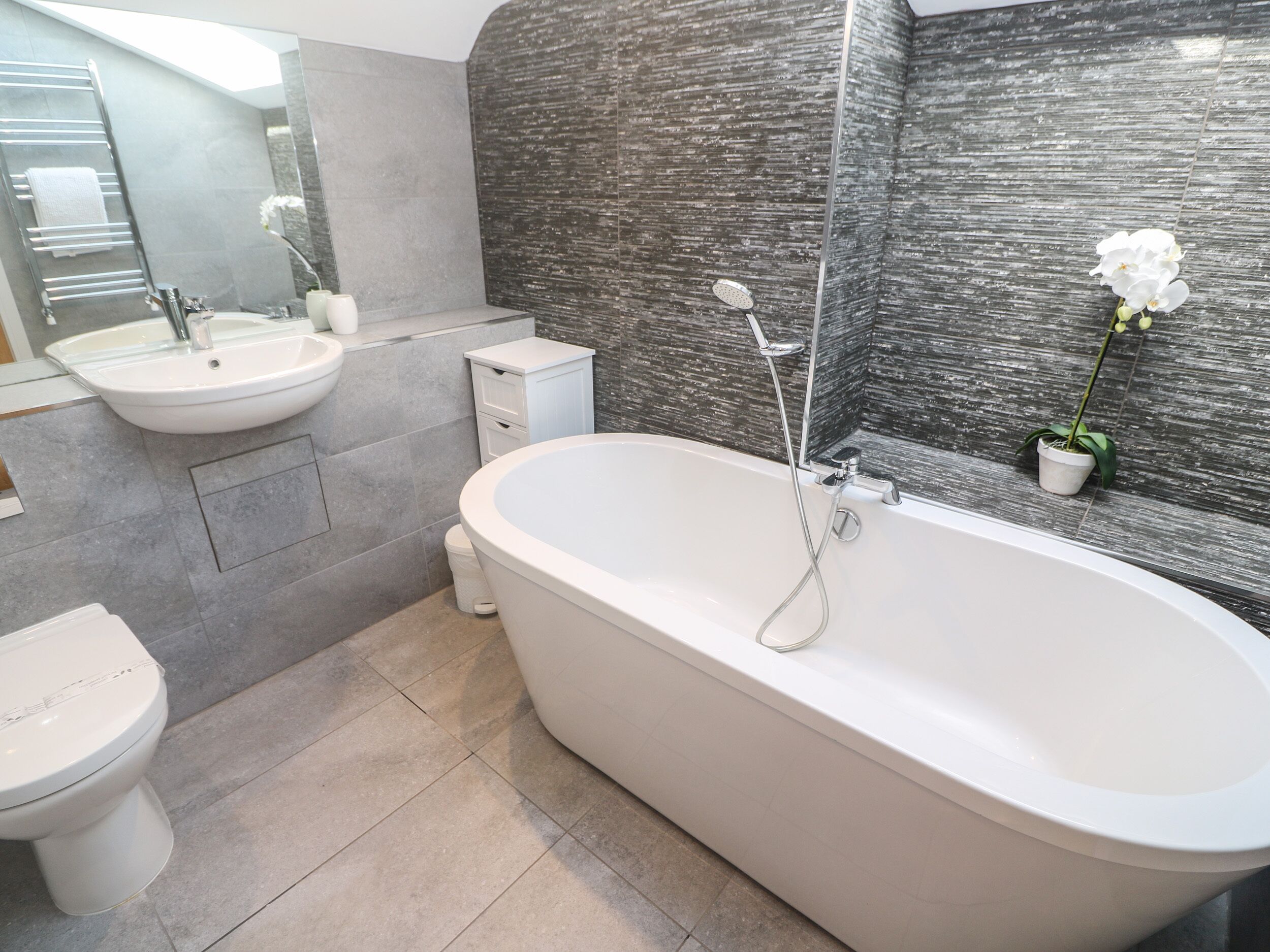 A modern bathroom with a freestanding bathtub, a sink, and a toilet.