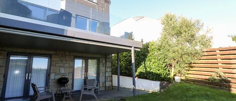 A modern house with a covered patio, stone walls, and a well-maintained lawn.