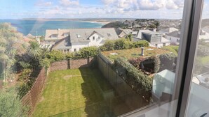 A residential area with houses, a grassy yard, and a view of the sea. - Seafield (St Ives)