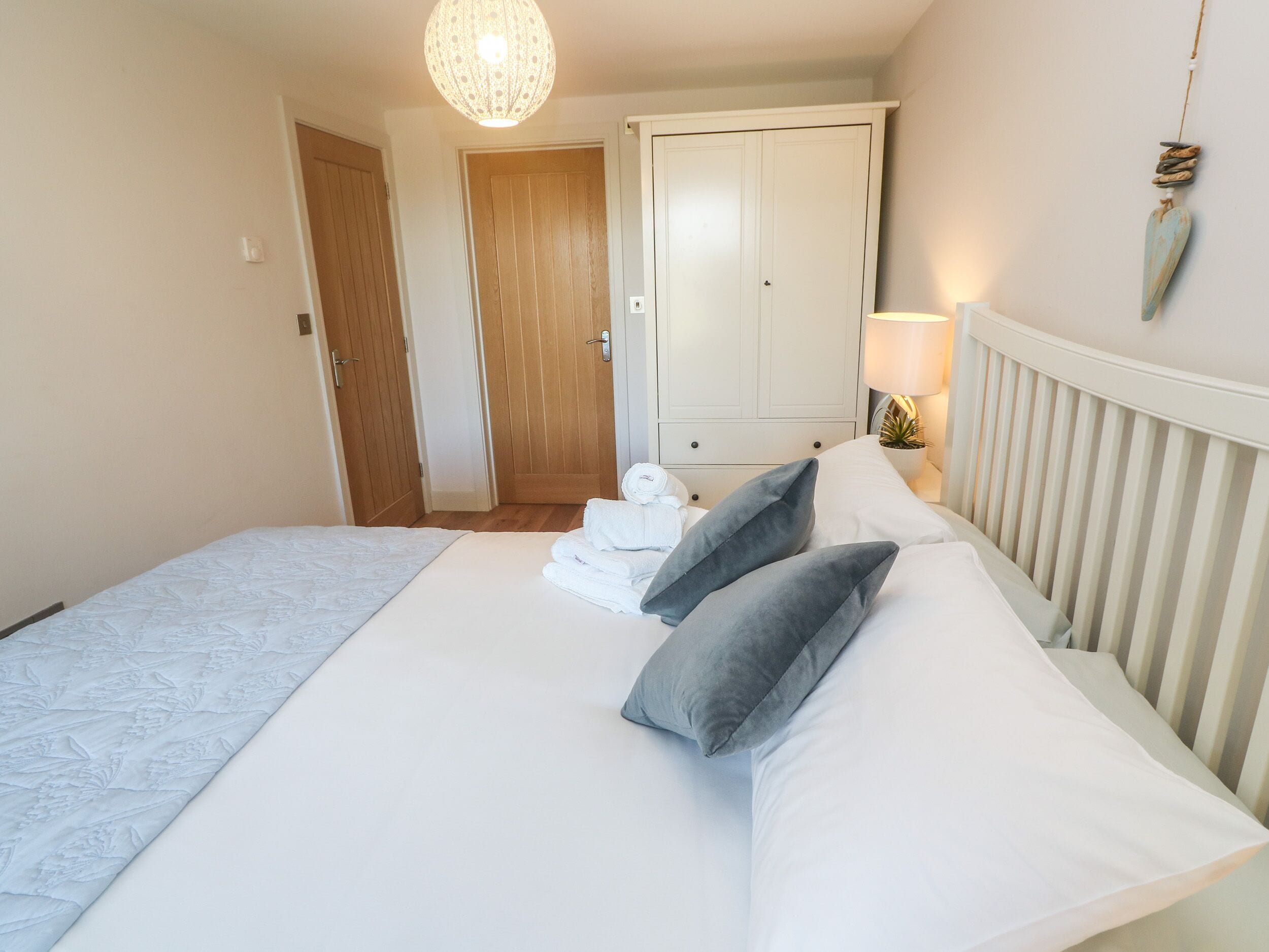 A bedroom with a bed, a bedside lamp, a wardrobe, and a door.