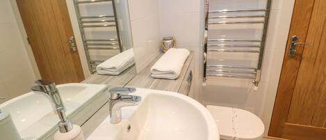 A modern bathroom with a large sink, a toilet, and a bathtub.