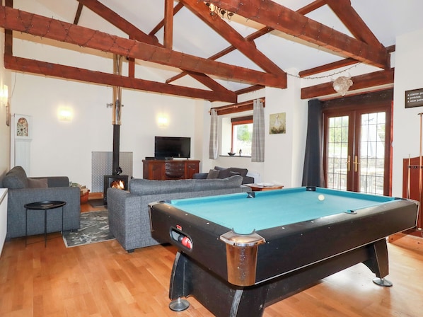 Una sala de estar acogedora con mesa de billar, chimenea y un espacio de descanso confortable.