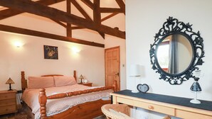 Quarto com cama de madeira, escrivaninha com espelho, cadeira de vime e piso estampado.