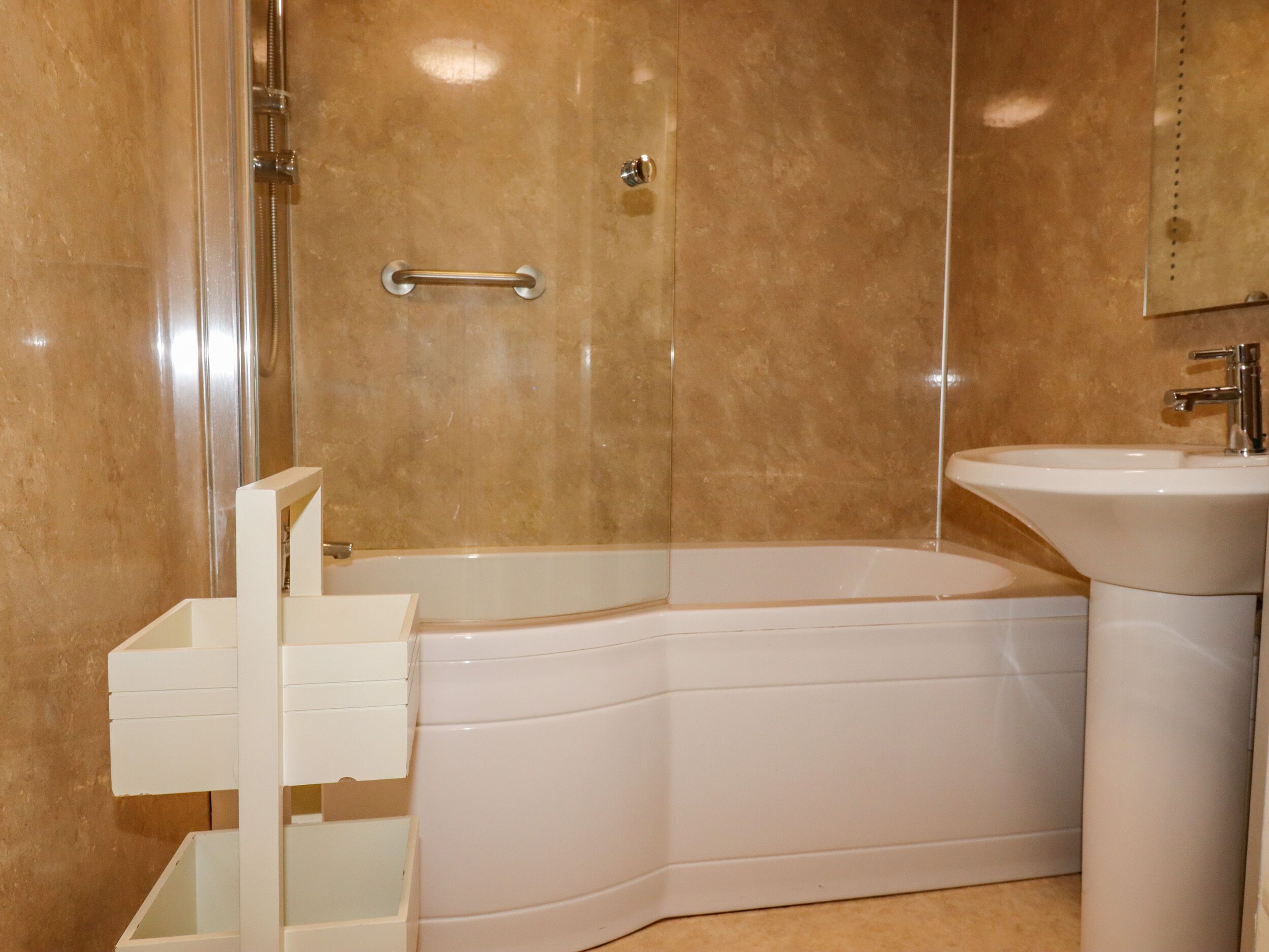 A modern bathroom with a corner bathtub, a white sink, and a glass-enclosed shower.