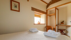 Ein Schlafzimmer mit einem großen Bett, einem Holzstuhl, einem Holzbodenregal und einem gerahmten Bild an der Wand.