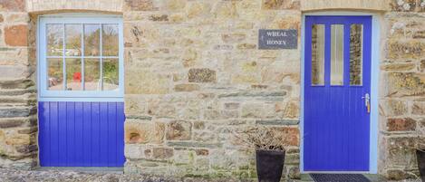 A stone building with two blue doors and a window.