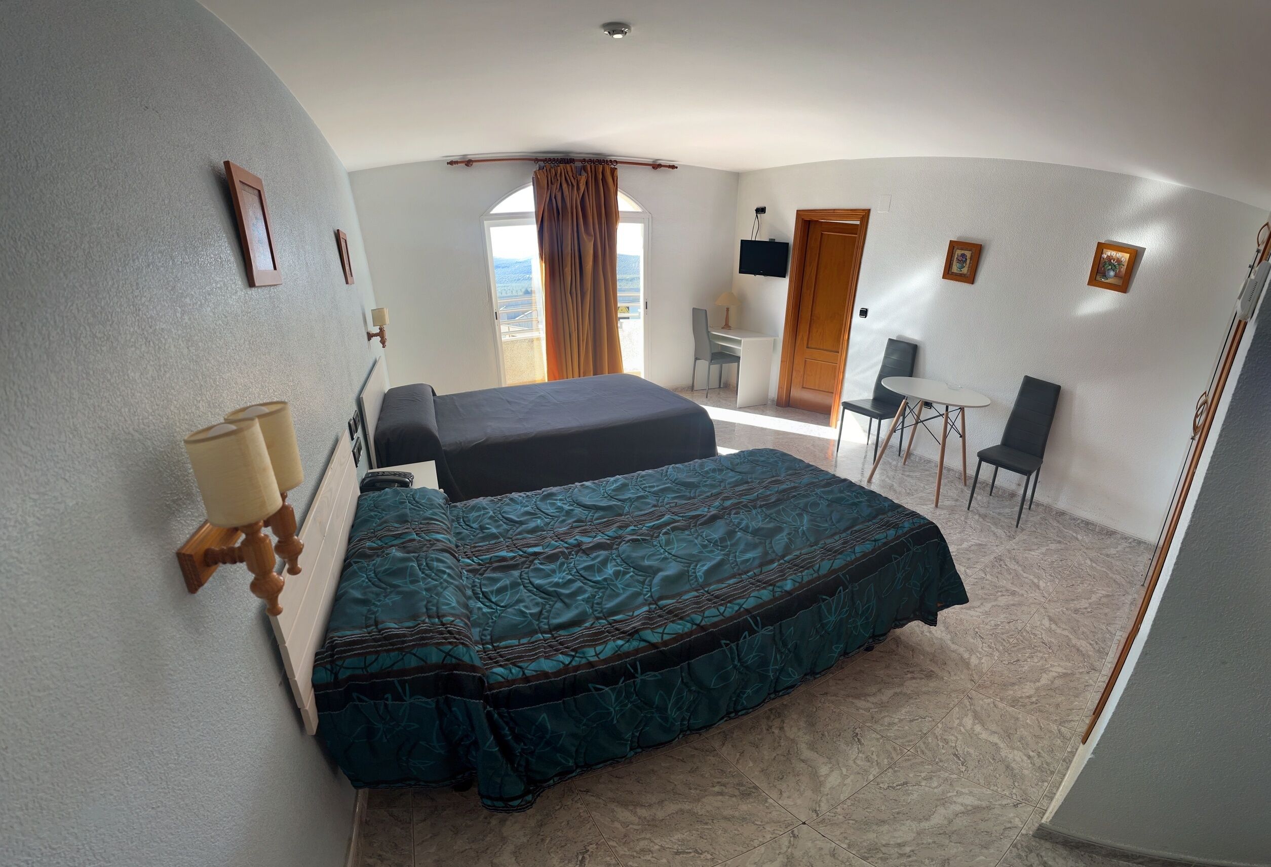A hotel room with a bed, a desk, a chair, and a TV.
