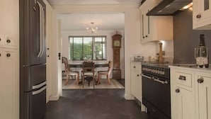 Eine Küche mit Kühlschrank, Herd und Essbereich mit Stühlen und Tisch.