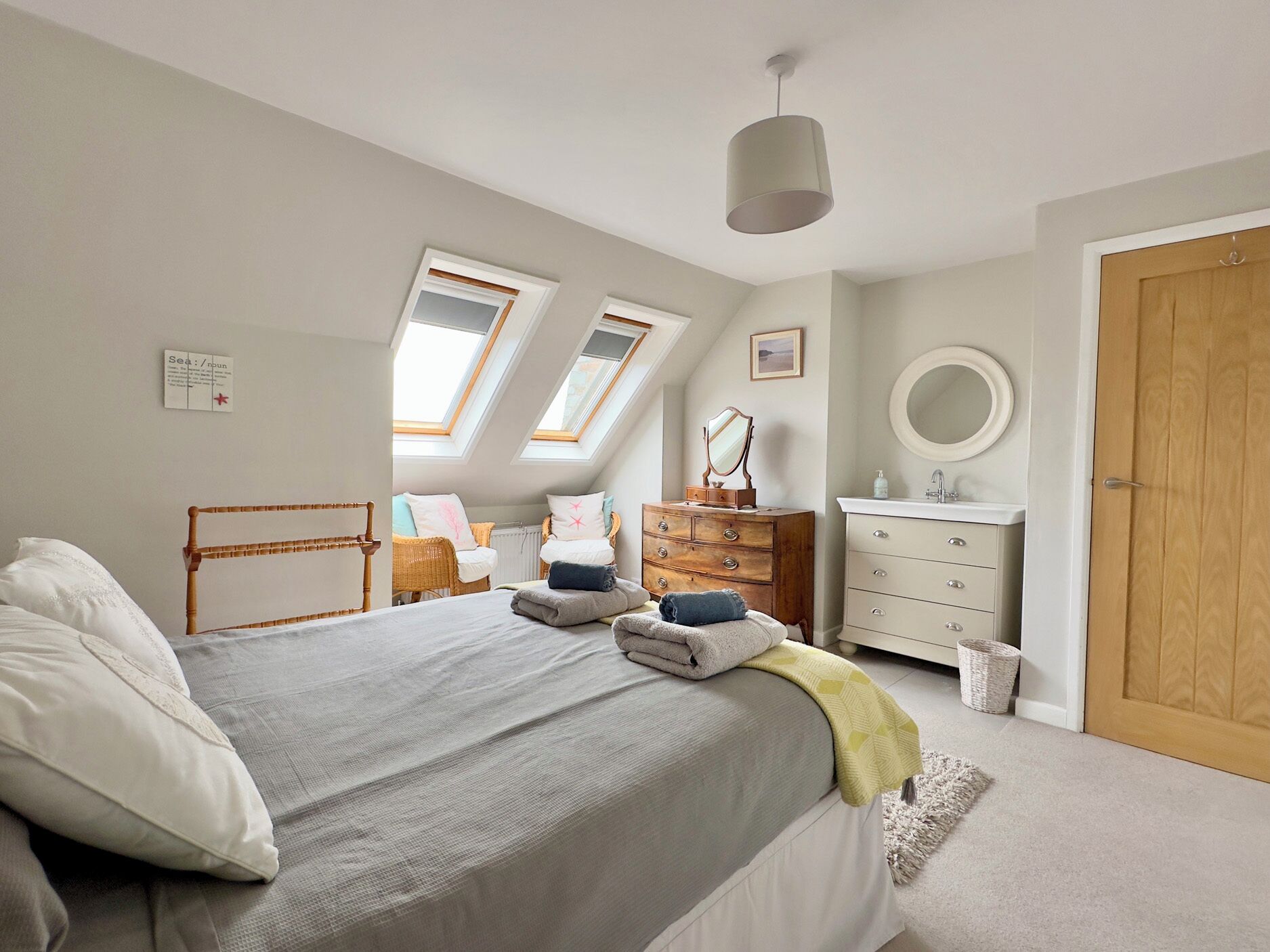 Une chambre à coucher avec un lit, une commode, un miroir et une porte.