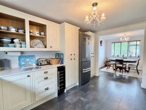 A modern kitchen with white cabinetry, a built-in dishwasher, a stainless steel refrigerator, and a dining area with a table and chairs.