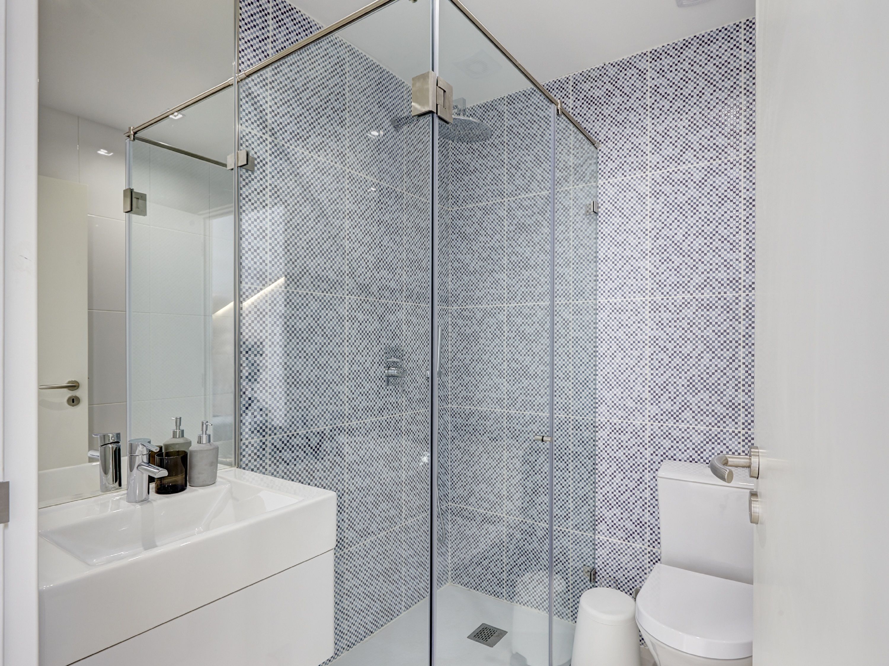 Une salle de bain moderne avec une douche à parois de verre, un lavabo blanc et des toilettes.
