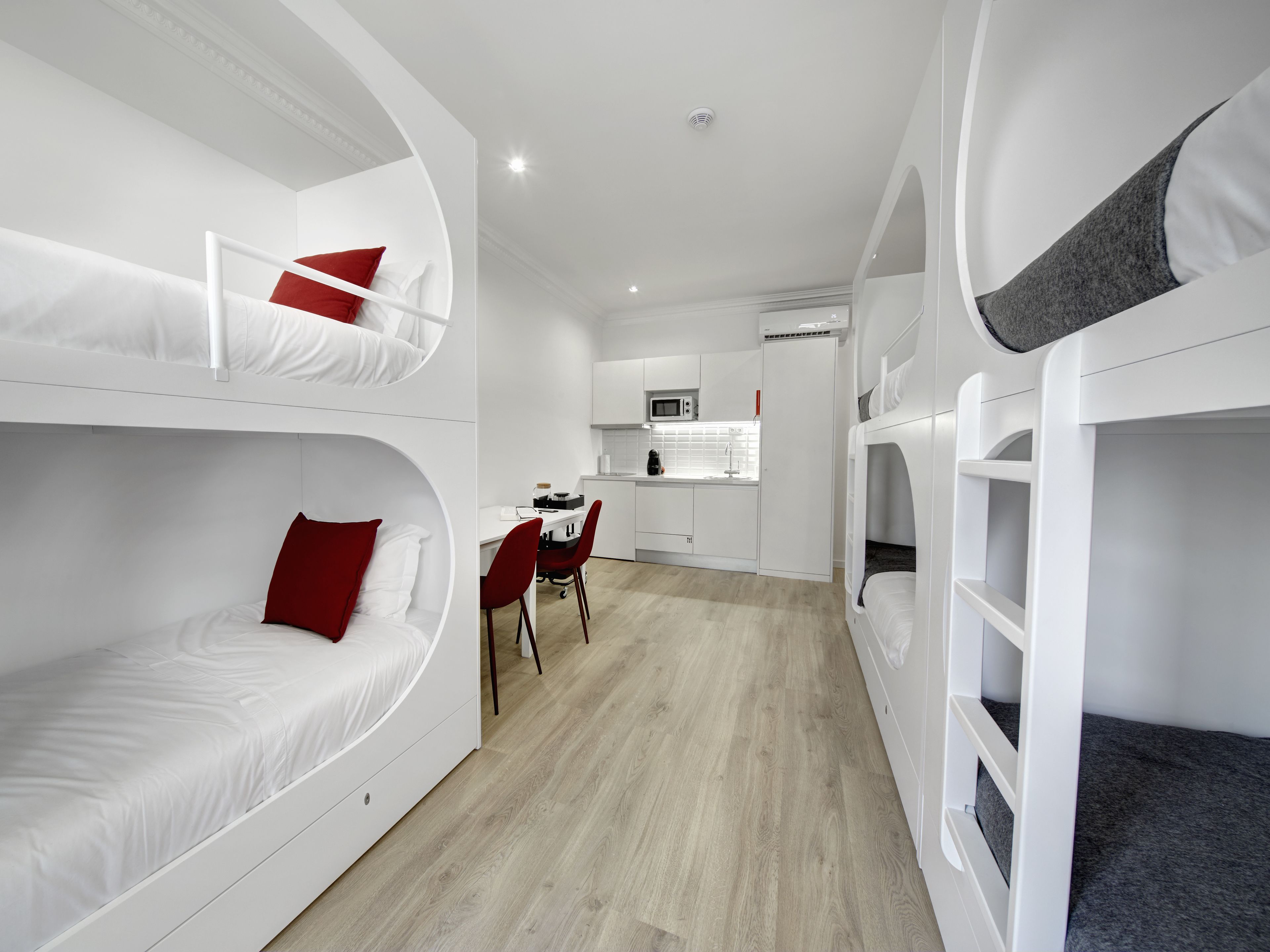 Une chambre compacte et moderne, dotée de lits superposés, d’une petite kitchenette et d’un coin repas.