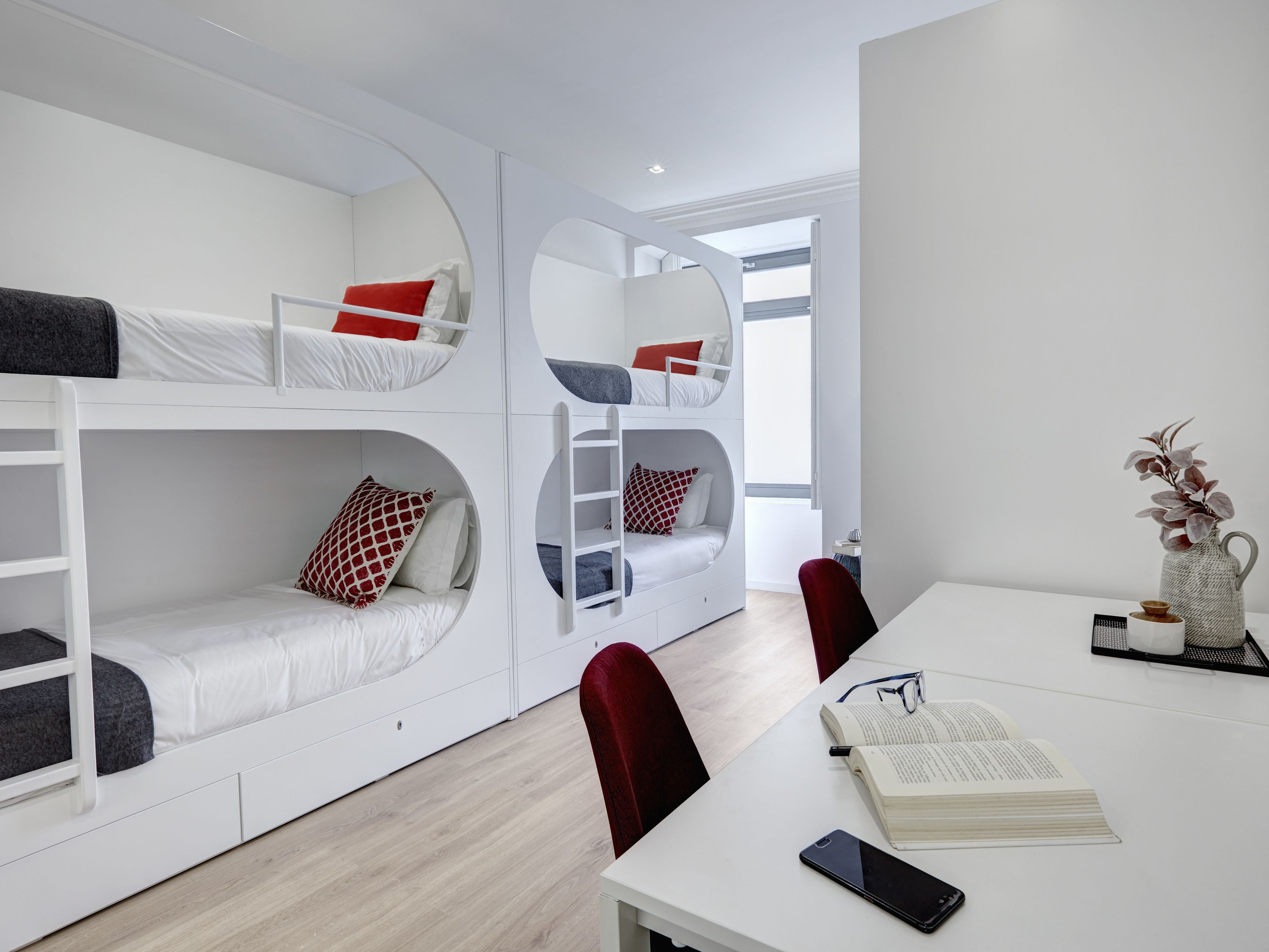 A modern room with bunk beds, a desk, and a chair.