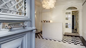 A hallway with a checkered floor, a white reception desk, and a decorative light fixture.