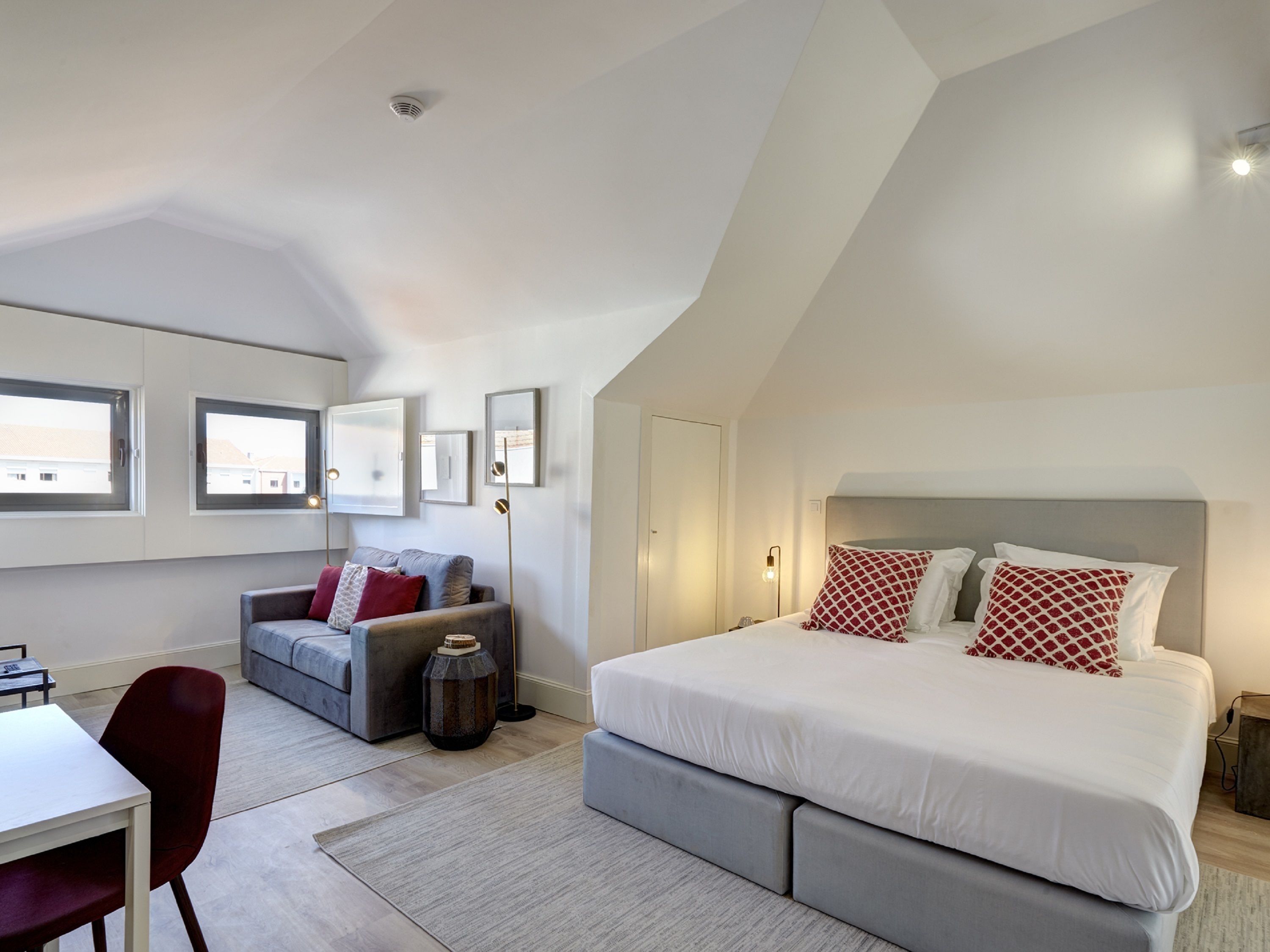 A modern bedroom with a large bed, a sofa, and a desk.