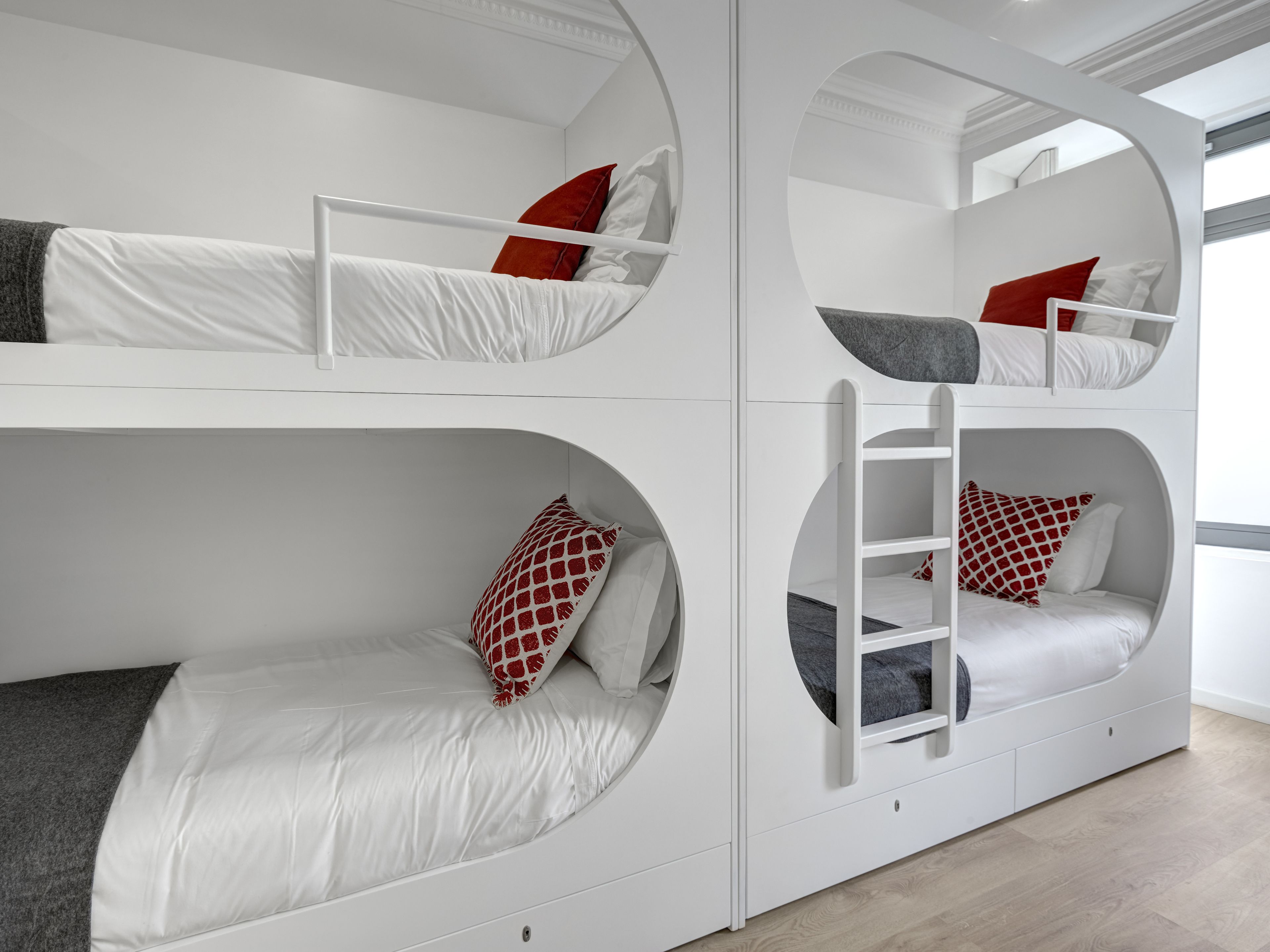 A bunk bed room with white walls and circular cutouts.