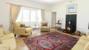 A living room with two cream-colored sofas, a patterned rug, a fireplace, and a framed picture on the wall. - Bannatyne Lodge (Blairgowrie)