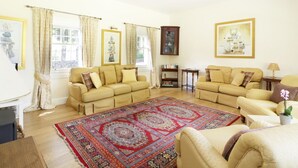A living room with two beige sofas, a red patterned rug, and a bookshelf. - Bannatyne Lodge (Blairgowrie)