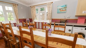 Un'area pranzo con sedie e tavolo in legno, una lavatrice e un quadro appeso al muro.