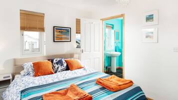 Un dormitorio con cama, ventana, puerta y baño visible a través de la puerta.
