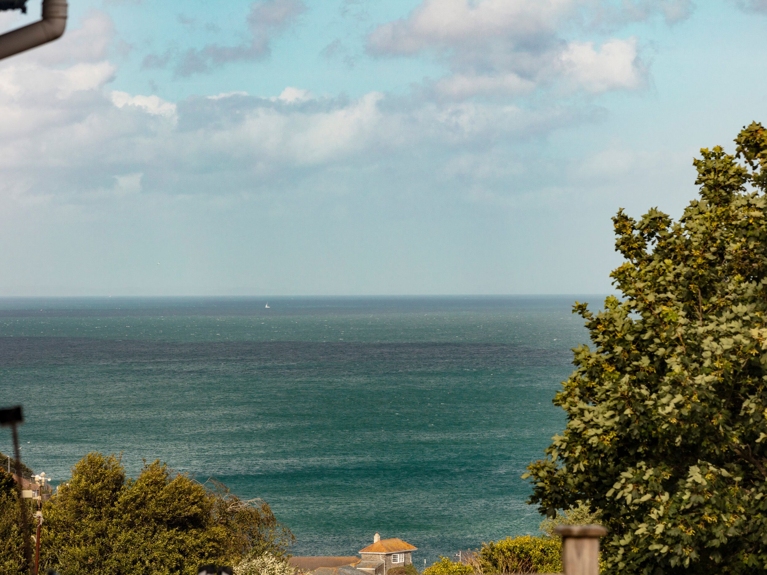 A coastal view with a house near the water, surrounded by greenery.