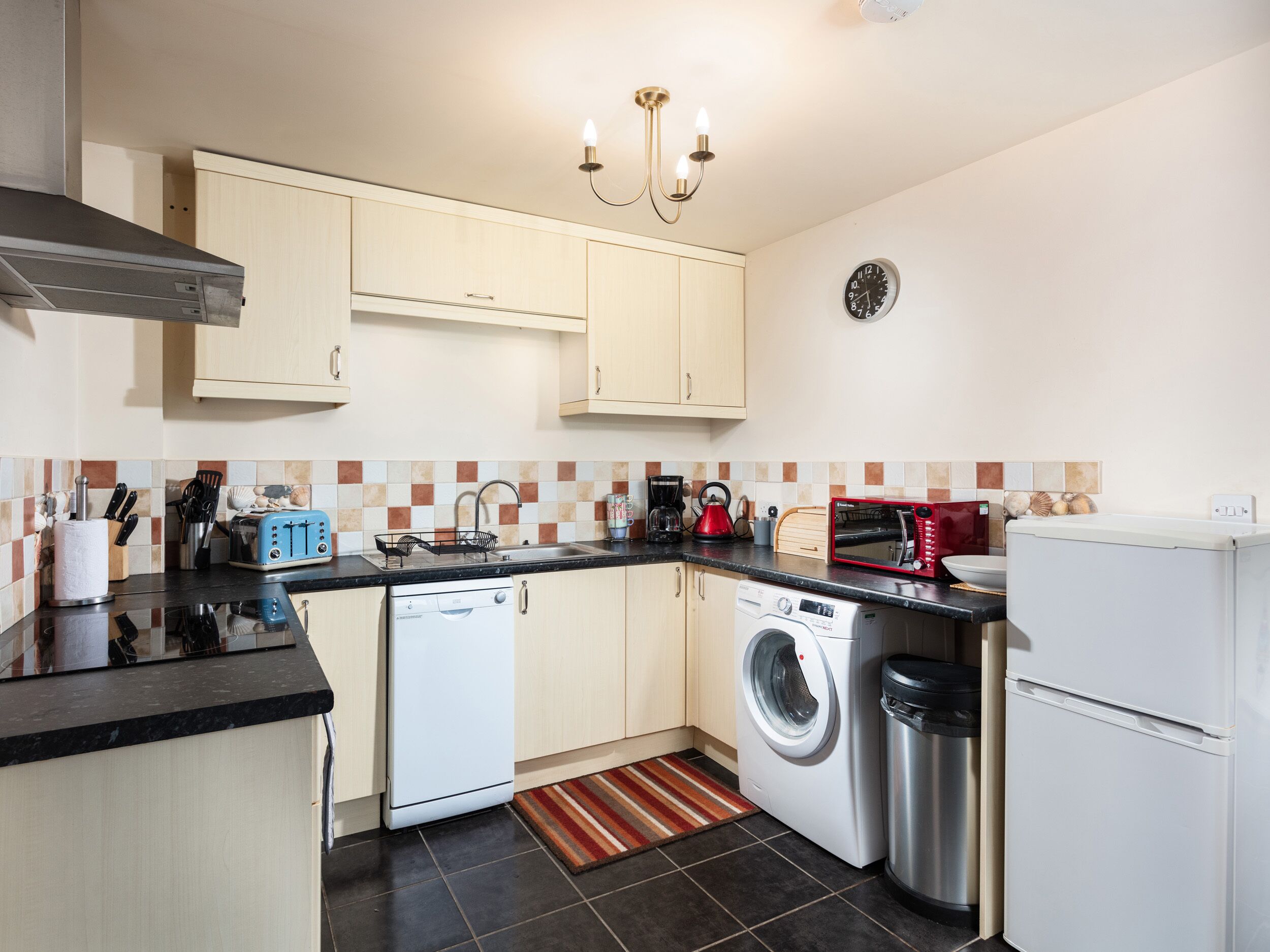 A compact kitchen with a dishwasher, washing machine, and a microwave.