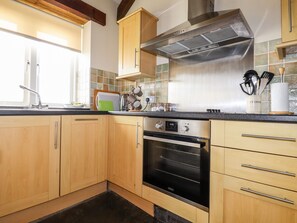 Une cuisine avec des armoires en bois, une hotte de cuisinière en acier inoxydable et un four noir.