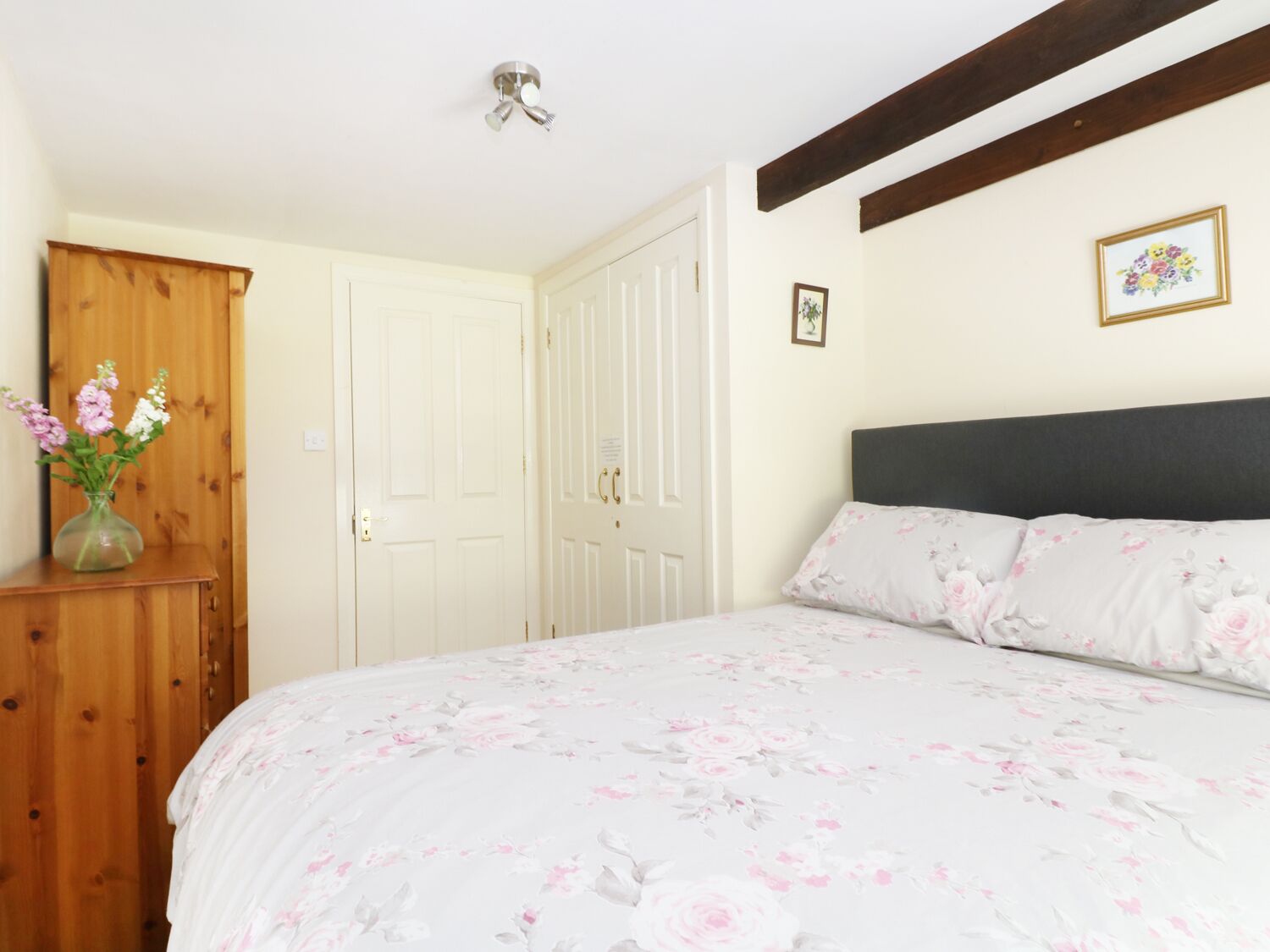 Un dormitorio con cama, armario de madera y detalles florales.