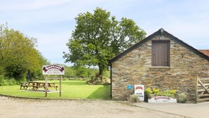 A rustic stone building with a wooden door and a sign indicating a bar. - Eastcott Farmhouse (Holsworthy)