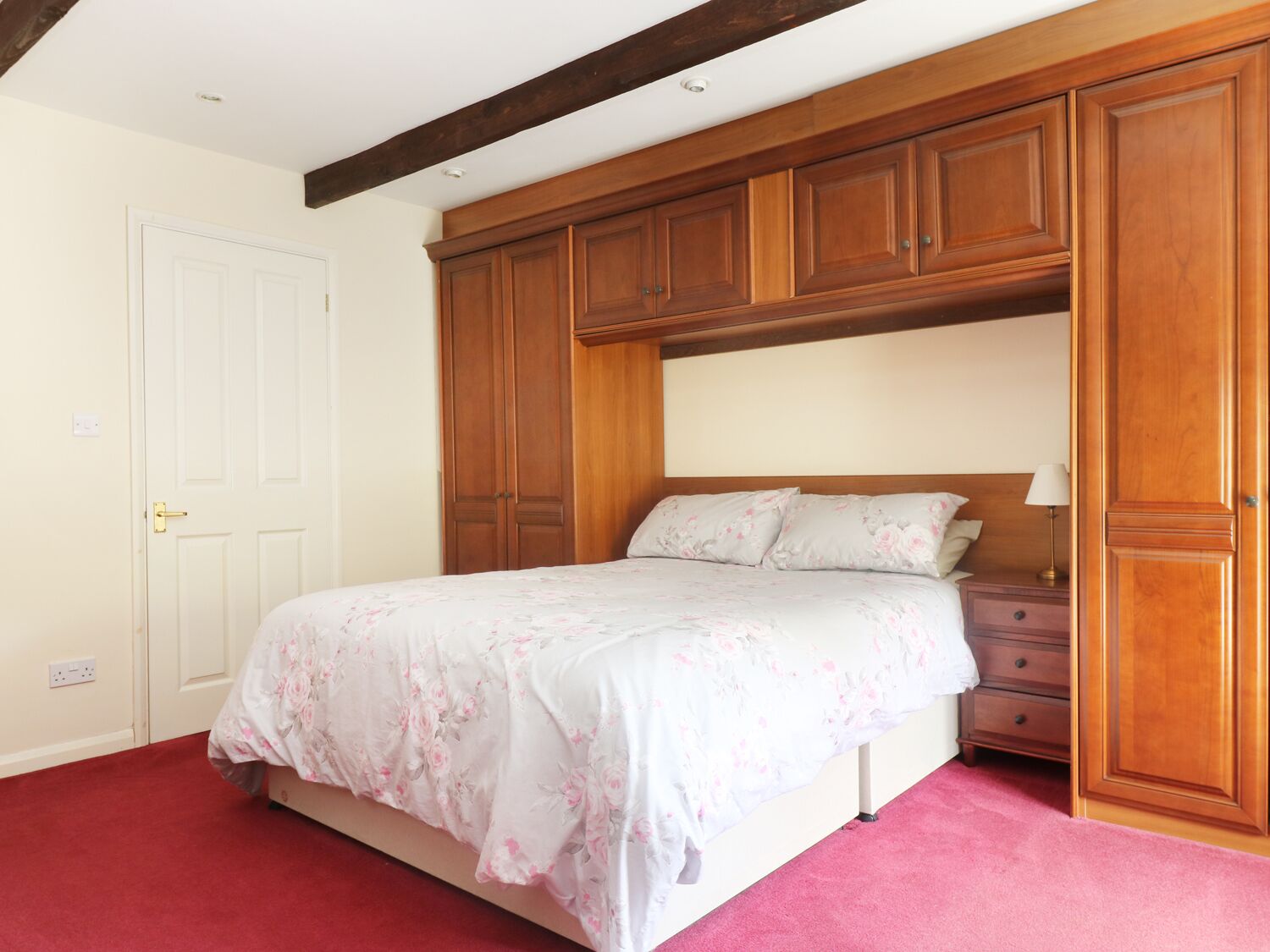 A bedroom with a bed, wooden wardrobe, and a nightstand.