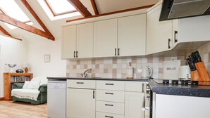 A kitchen with white cabinets, a built-in dishwasher, and a coffee maker. - Brocks Barn (Bodmin)