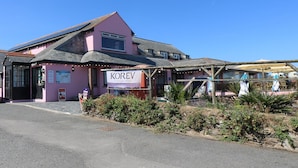 A pink building with a sign reading "KOREV Cornish Lager with Soul".