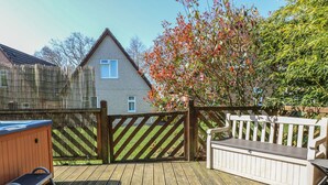 Eine Holzterrasse mit Whirlpool, Holzzaun und einer Sitzbank.