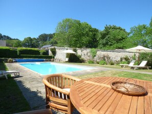 En baghave med swimmingpool, træterrasse og liggestole.