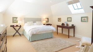 A bedroom with a bed, bedside tables, a desk, a dresser, a window, and framed pictures on the wall. - Farm Cottage (Hayle)
