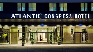 The exterior of the Atlantic Congress Hotel with a modern glass facade, large potted plants, and a well-lit entrance. - Atlantic Congress Hotel Essen, WorldHotels Elite (Essen)