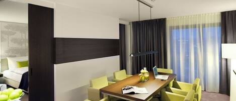 Habitación de hotel moderna con comedor que incluye una mesa de madera y cuatro sillas.