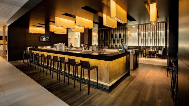 A modern bar area with a long counter, bar stools, and overhead lighting. - Atlantic Congress Hotel Essen, WorldHotels Elite (Essen)