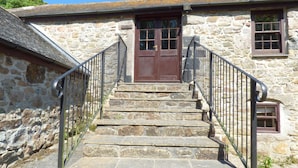 A stone staircase leading to a wooden door with a window above it. - The Granary (Hayle)