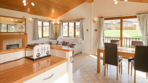A cozy kitchen with wooden cabinets, a built-in stove, and a dining area with a table and chairs. - High Tide (Wadebridge)