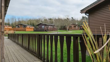 A wooden deck with a view of several cabins and a grassy area.