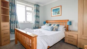 Une chambre à coucher avec un lit en bois, une table de chevet avec une lampe, une armoire et une fenêtre avec des rideaux.