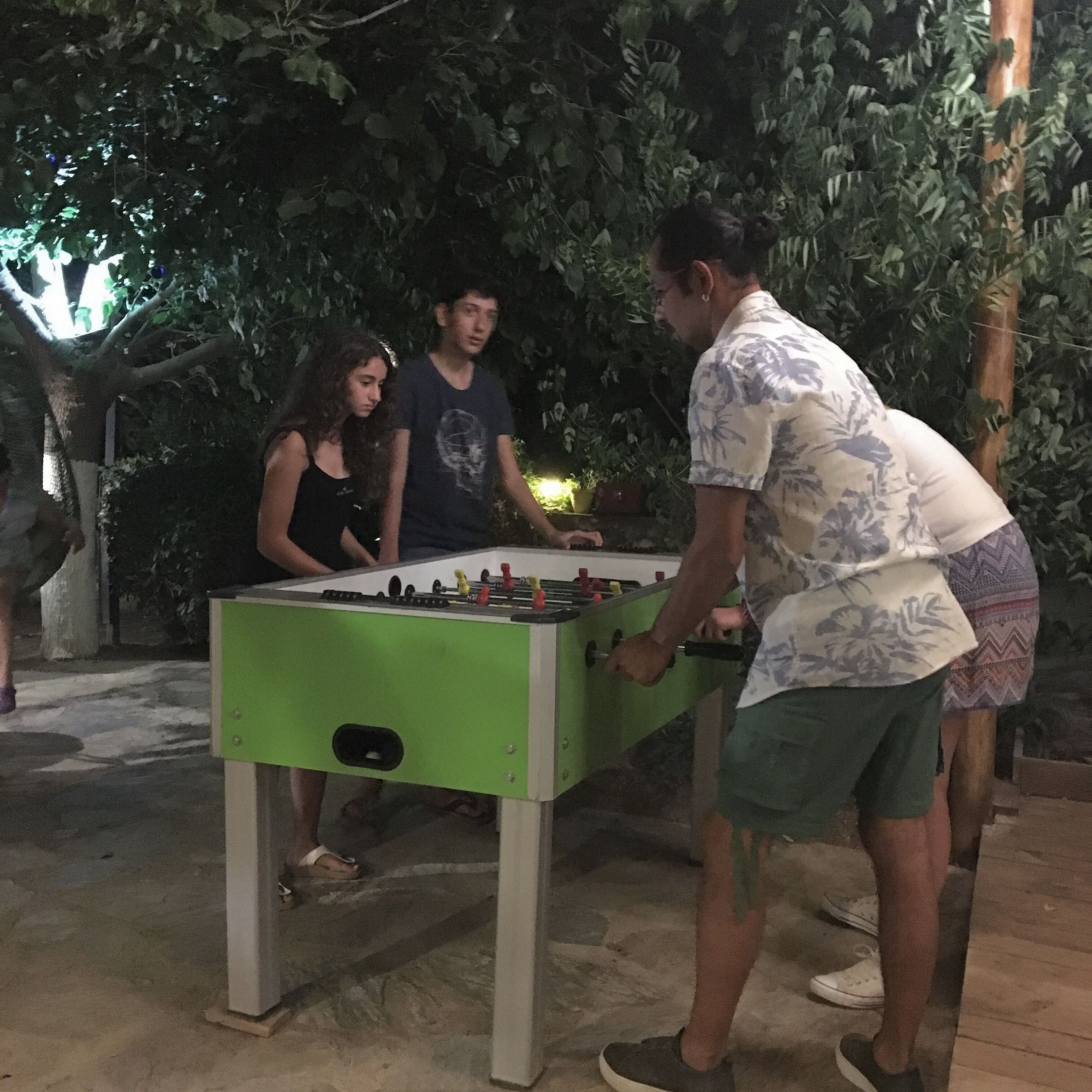 Un grupo de personas jugando al fútbol de mesa al aire libre de noche.
