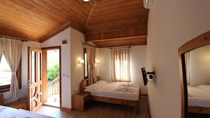 A wooden-paneled bedroom with two beds, a TV, and a balcony door. - Elly's Home (Datça)