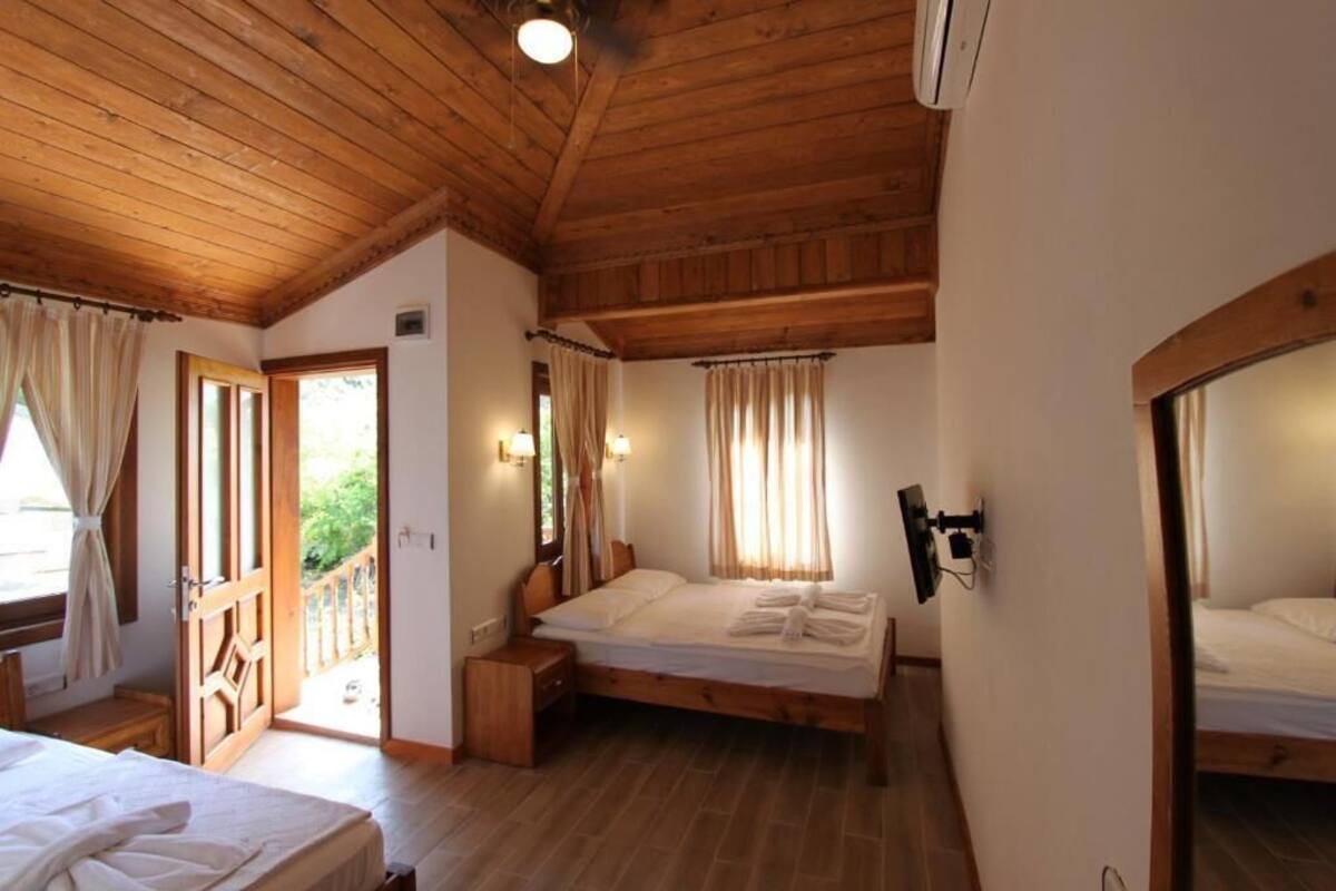 Un dormitorio con paneles de madera, dos camas, un televisor y una puerta al balcón.
